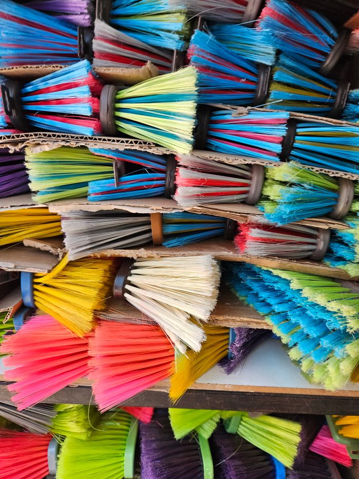 A vibrant collection of colorful broom heads stacked together, showcasing a rainbow of hues.